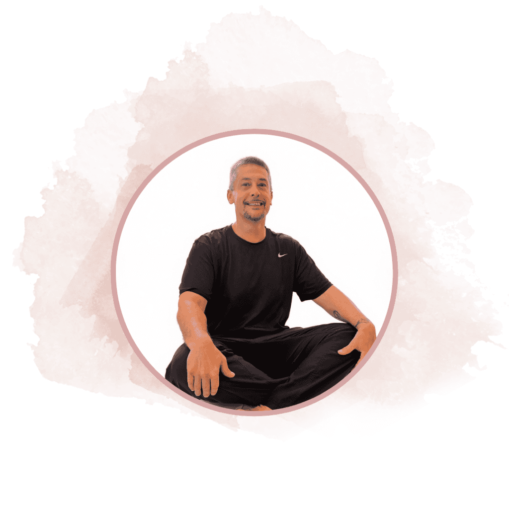 Smiling man sitting cross-legged in a black t-shirt inside a pink circular frame with a watercolor splash background.
